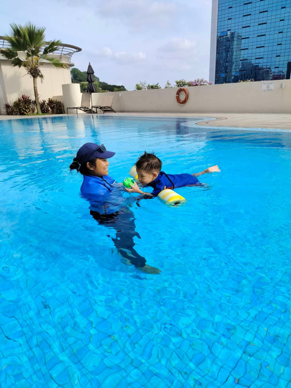 A child learning to float with their instructor at Mulberry Clarke Quay