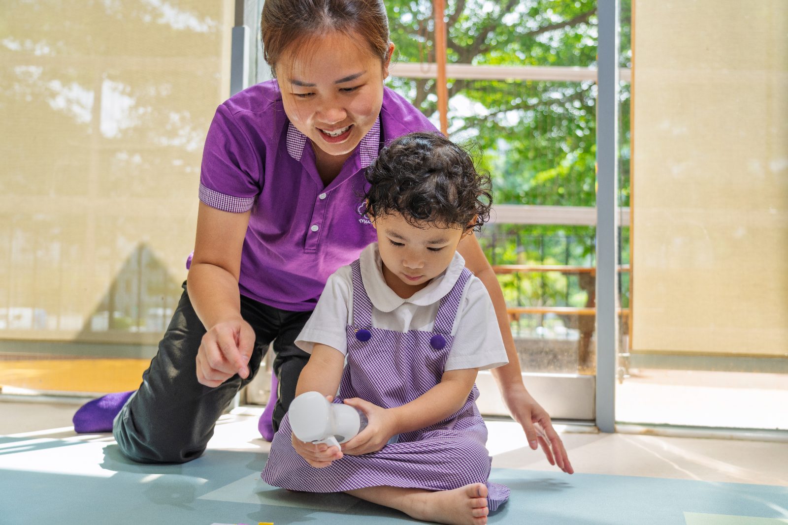 A Mulberry teacher guiding a young child during inquiry play