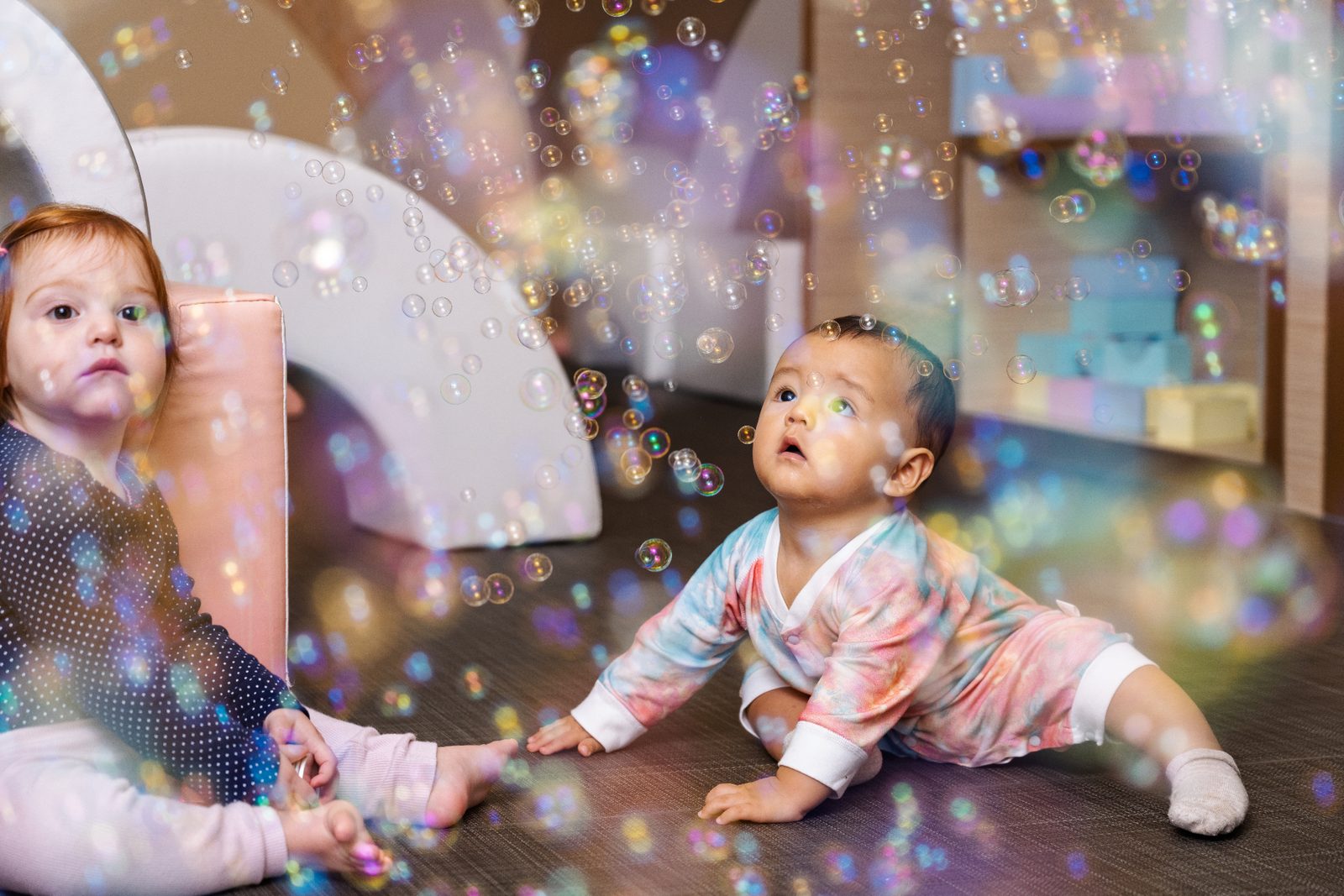 An infant exploring sensory play with bubbles in a bright classroom
